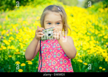 Petite fille à prendre des photos sur un pré Banque D'Images