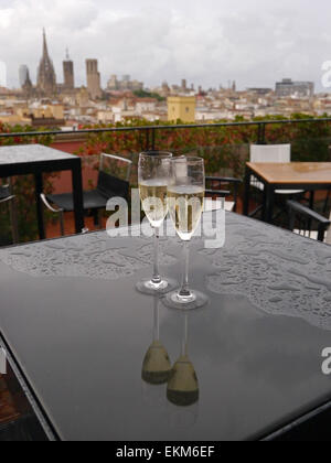 Verres de champagne sur une table sous la pluie avec des réflexions Banque D'Images