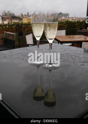 Verres de champagne sur une table sous la pluie avec des réflexions Banque D'Images