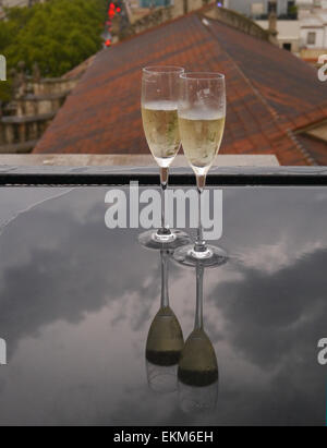 Verres de champagne sur une table sous la pluie avec des réflexions Banque D'Images
