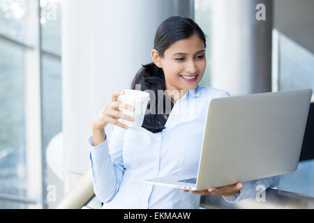 Closeup portrait, jeune, jolie femme debout, boire du café, souriant à l'ordinateur portable, le surf d'argent. Banque D'Images