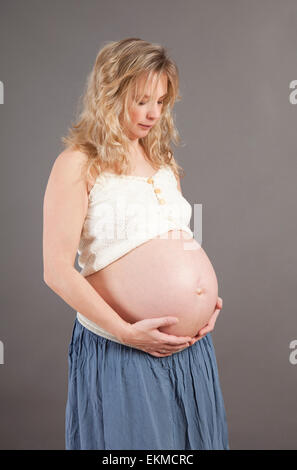 Une jeune blonde pregnant woman holding her baby bump Banque D'Images