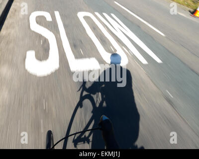 Cyclisme vers SLOW sign painted on road Banque D'Images