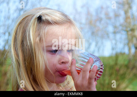 Close up of enfant fille blonde de boire de la limonade à l'extérieur de l'heure d'été Banque D'Images