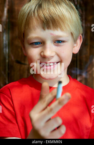 Portrait d'enfant garçon blond cigarette avec fond en bois sombre derrière lui Banque D'Images