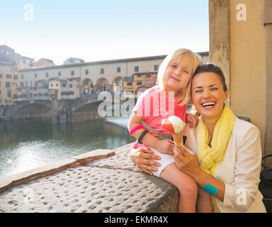 Portrait of happy mother and baby girl eating ice cream près de Ponte Vecchio à Florence, Italie Banque D'Images