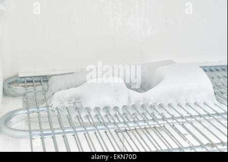 Le temps de décongeler une glace laden congélateur inefficace avec des couches de glace de l'eau gelée sur les éléments et la durée de l'intérieur Banque D'Images