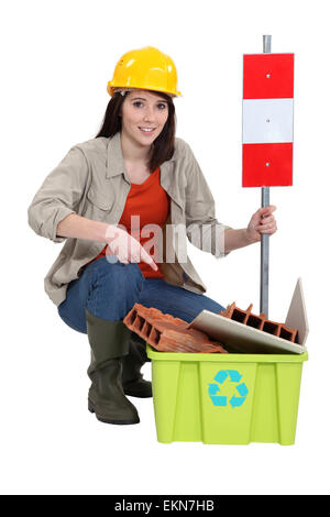 Female construction worker vous avertissant de recycler d'anciens matériels Banque D'Images