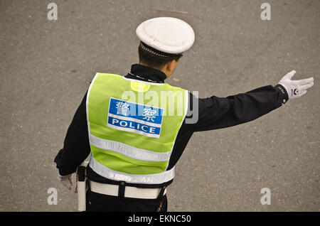 Un jeune agent de police dirige le trafic sur une route très fréquentée à l'heure de pointe dans la région de Xi'an, Chine. Banque D'Images