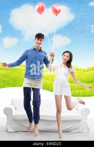 Happy young couple jumping with balloon Banque D'Images