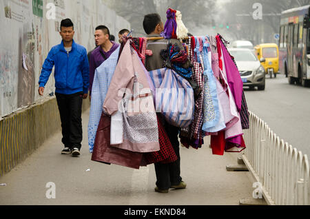 Vieux homme marche dans les rues vendant des vêtements et à Xi'an, Chine. Banque D'Images