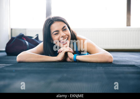 Femme allongée sur le sol. montrant sa langue et clignant de. Looking at camera Banque D'Images