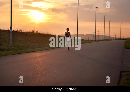 Adolescent triathele fonctionnant dans le cadre d'une course de duathlon avec coucher de soleil en arrière-plan à Gravesend Cycloparc PPJ d'avance Banque D'Images