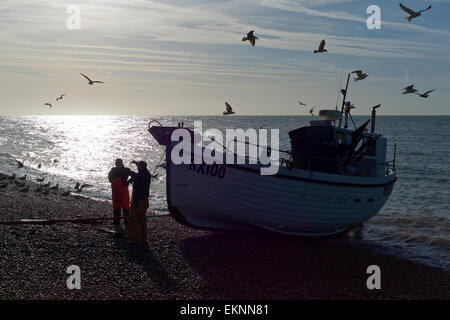 Les pêcheurs de discuter leurs prises à côté de leur bateau sur la plage, Hastings, Royaume-Uni. Forte ossature, mer calme. Banque D'Images