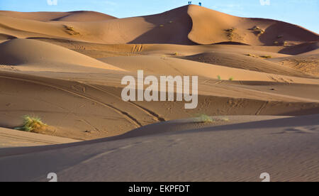 Deux personnes admirer le coucher de soleil depuis une colline. Plusieurs dunes de l'Erg Chebbi dans le désert du Sahara. Ers sont de grandes dunes formées par w Banque D'Images