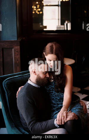 Un couple sur une date, une femme embrassant un homme assis sur une chaise. Banque D'Images