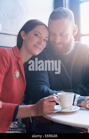 Un couple assis côte à côte à une table de café. Banque D'Images