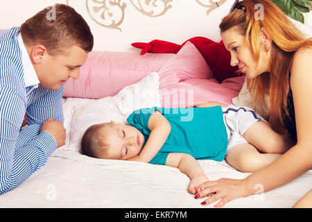 Heureux parents et cute baby sleeping on bed Banque D'Images