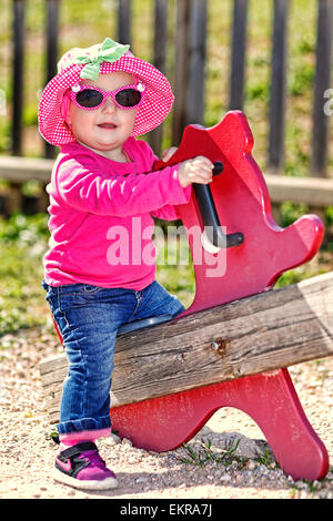 Une jolie petite fille avec des lunettes roses et hat s'amusant Banque D'Images