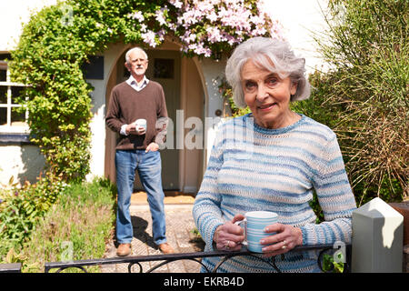 Senior Couple Standing In Chalet jardin avec tasses à café Banque D'Images