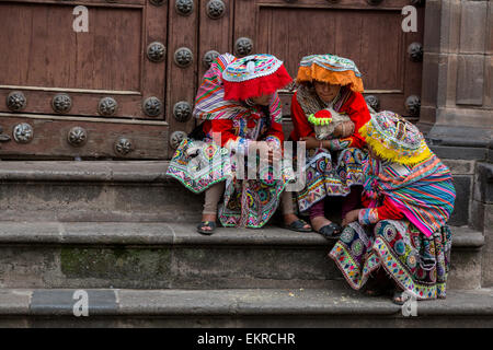 Pérou, Cusco. Les jeunes femmes quechua en costume traditionnel assis sur le perron de l'église. Banque D'Images