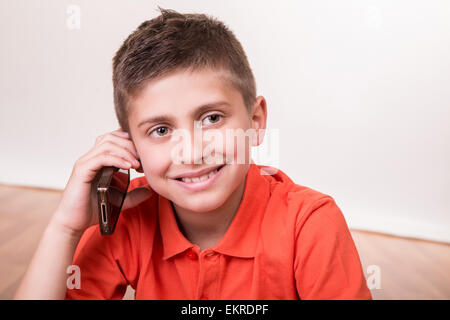 Blonde cute boy appelant à partir de son téléphone cellulaire Banque D'Images