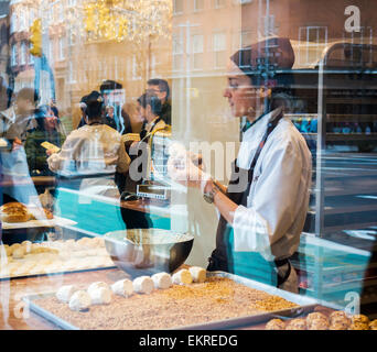 Une pâtisserie prépare merveilleux (wonderfuls) dans la fenêtre de l'établissement aux merveilleux de Fred à Greenwich Village à New York le Dimanche, Avril 5, 2015. Merveilleux sont confections fait de deux meringues collées ensemble avec la crème fouettée, puis enduit de crème fouettée puis enrobées de chocolat ou d'autres saveurs. (© Richard B. Levine) Banque D'Images