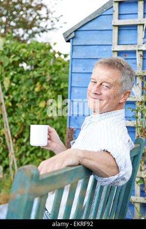 Senior Woman Relaxing In Jardin avec tasse de café Banque D'Images