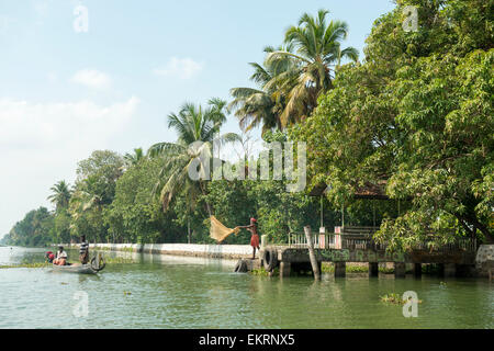 Un pêcheur casting son filet sur les backwaters de Kumarakom, Kerala Inde Banque D'Images