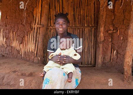 Une femme tenant son bébé à l'extérieur d'une maison ; Manica, Mozambique, Africa Banque D'Images