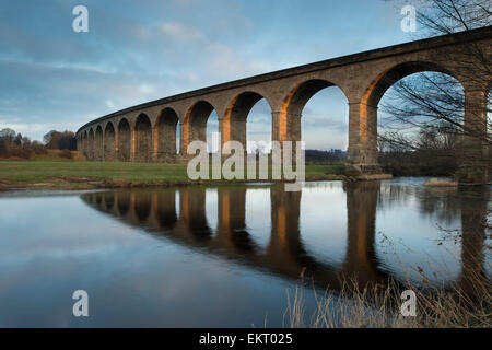 Dans le cadre de ciel bleu, des arches de pont ferroviaire Viaduc Arthington se reflètent dans les eaux calmes de la rivière Wharfe - West Yorkshire, Angleterre, Royaume-Uni. Banque D'Images