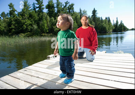 Mère autochtone sur un quai avec son fils à Shoal Lake, Ontario, Canada. Banque D'Images