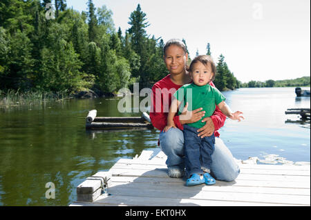 Mère autochtone sur un quai avec son fils à Shoal Lake, Ontario, Canada. Banque D'Images