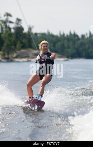 Femme d'âge moyen wakeboard sur Gunn Lake, Ontario, Canada. Banque D'Images