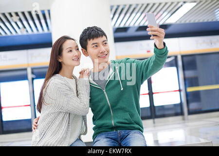 Young couple taking self portrait at subway station Banque D'Images
