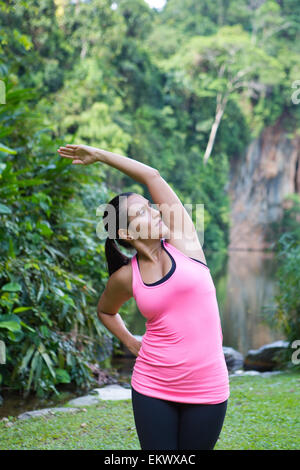 Femme sportive s'étend du côté gauche du corps après l'exercice en extérieur parc Banque D'Images