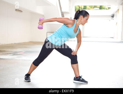 Beau sport femme en bleu avec haltère triceps extension faisant retour d'exercice Banque D'Images