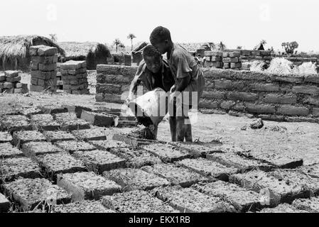 Les jeunes garçons à faire des briques de boue dans la construction de huttes à Kenema Sierra Leone 1993 Banque D'Images