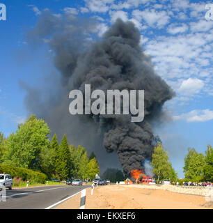 Chariot en feu avec fumée noire sur la route Banque D'Images