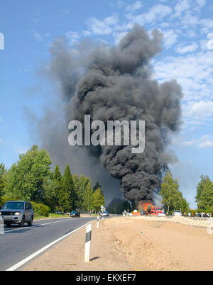 Chariot en feu avec fumée noire sur la route Banque D'Images