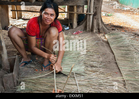 Femme cambodgienne le tissage des feuilles de palmier pour faire un toit de maison à Kep, au Cambodge. Banque D'Images