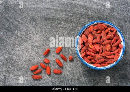 Sécher les baies de goji dans petite tasse sur tableau noir Banque D'Images