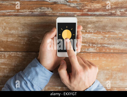 Close up of hands avec icône soleil sur smartphone Banque D'Images