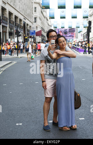 London UK selfies : mari et femme en tenant un téléphone intelligent Apple avec selfies dans Regent Street, Londres. Banque D'Images