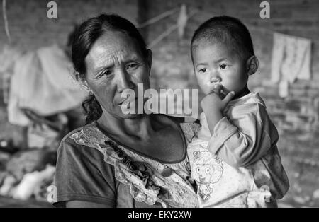 Une femme tenant un jeune enfant ; la Chine Yunnan Ruili Banque D'Images