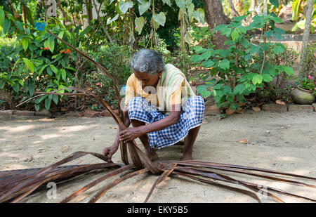 Une vieille femme indienne tisse un mat dans le cadre d'une authentique expérience de village pour les touristes à Kumarakom, Kerala, Inde Banque D'Images
