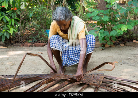 Une vieille femme indienne tisse un mat dans le cadre d'une authentique expérience de village pour les touristes à Kumarakom, Kerala, Inde Banque D'Images