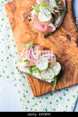 Les sandwiches ouverts avec du jambon, concombre, roquette et fromage sur une tranche de pain de seigle grillé au bois d'olive, vue d'en haut Banque D'Images