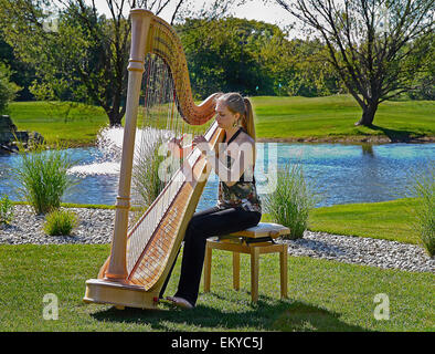 Jeune femme jouant de la harpe sur un parcours de golf. Banque D'Images