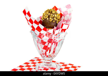 Cornet de crème glacée au chocolat et noix dans du verre plat sundae bordée de papier à carreaux rouge et blanc isolé sur blanc. Banque D'Images